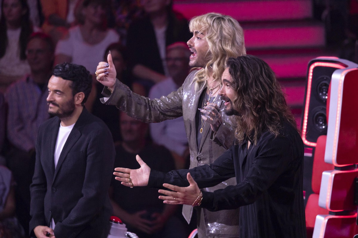 Giovanni lächelt, Bill und Tom Kaulitz sehen aufgeregt aus