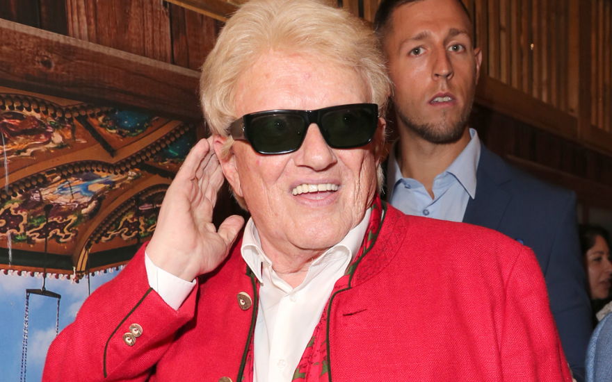 Heino lacht mit Sonnenbrille und fasst sich ans Ohr