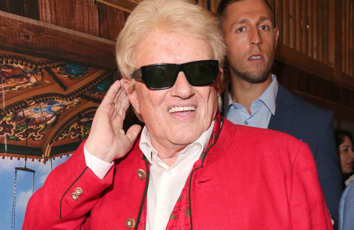 Heino lacht mit Sonnenbrille und fasst sich ans Ohr