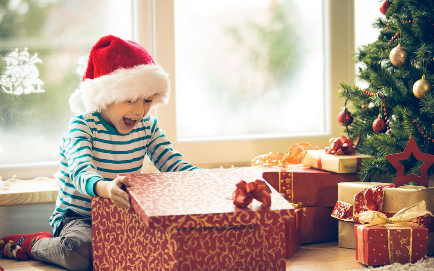 Kind öffnet Weihnachtsgeschenk und freut sich