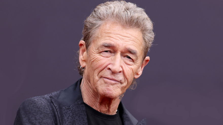 Peter Maffay guckt vor einem lila Hintergrund ernst in die Kamera