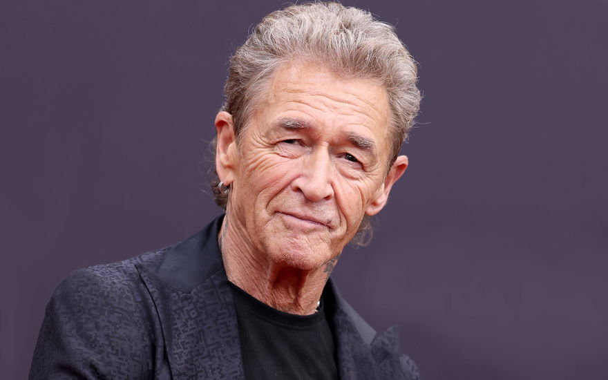 Peter Maffay guckt vor einem lila Hintergrund ernst in die Kamera