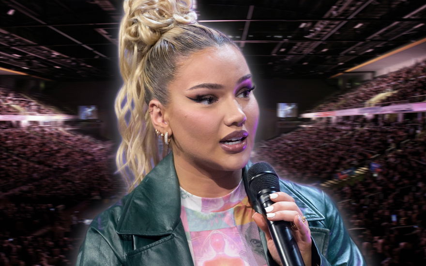 Shirin David spricht am Mikrofon, im Hintergrund ist eine gefüllte Konzerthalle