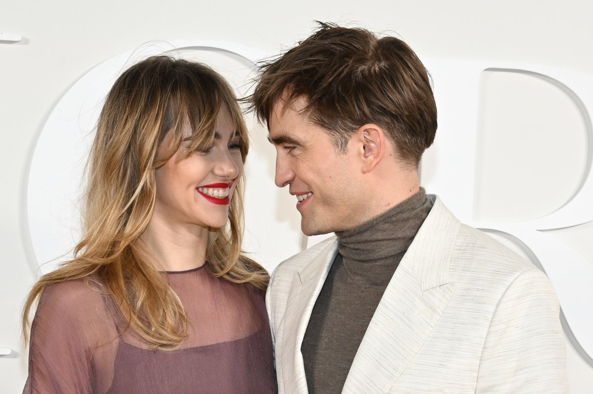 Robert Pattinson und Suki Waterhouse lächeln sich an