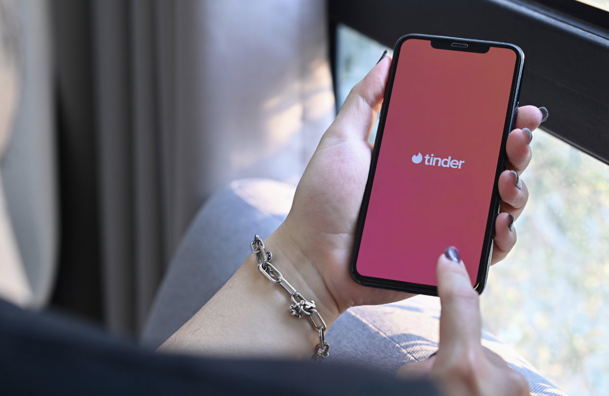 Frau hält Smartphone mit Tinder-App in der Hand