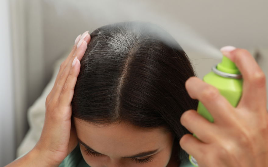 Frau benutzt Trockenshampoo