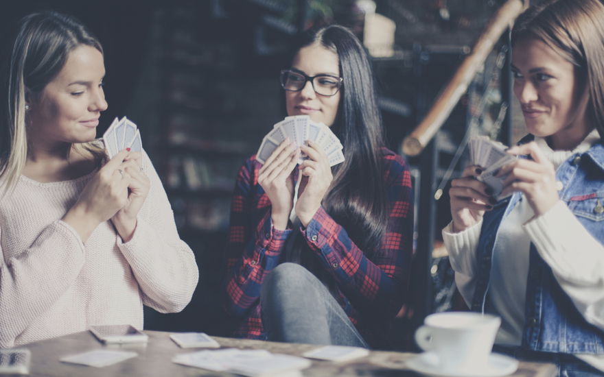 3 Frauen spielen mit karten im Café