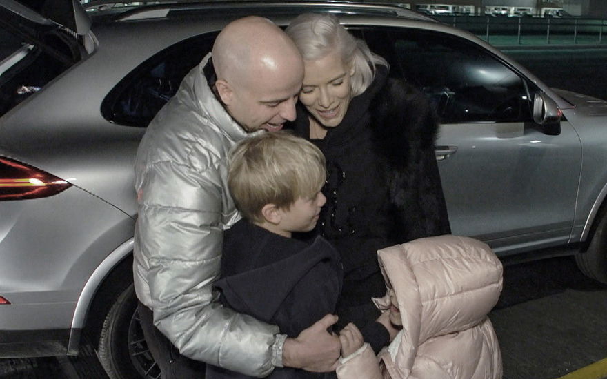 Daniel und Oksana Kolenitchenko umarmen ihre Kinder draußen vor einem Auto