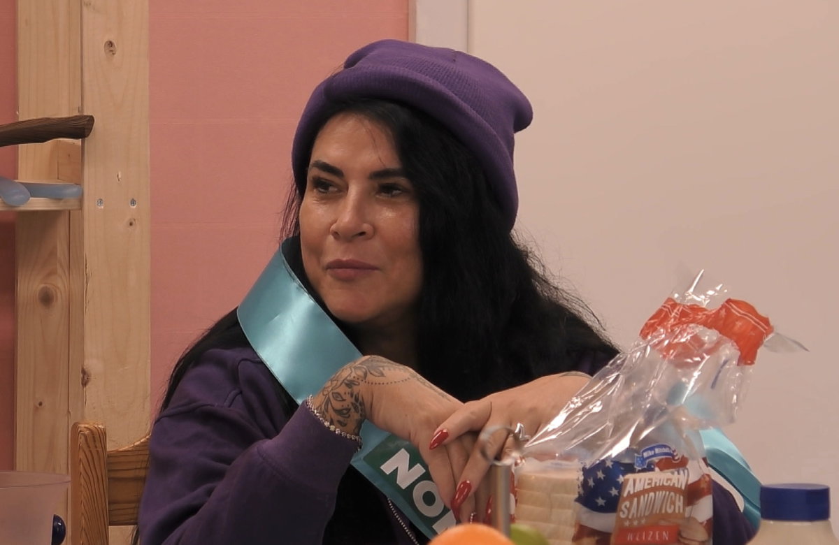 Iris Klein sitzt am Tisch bei "Promi Big Brother" und guckt ernst