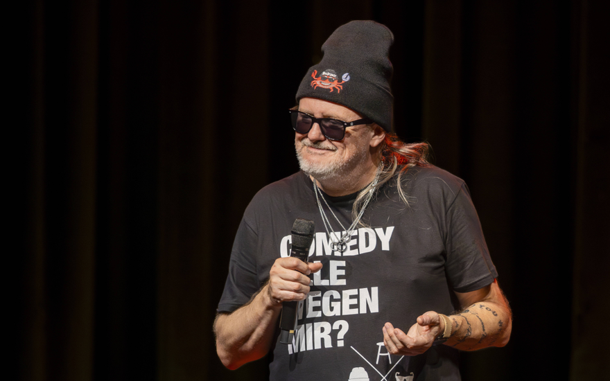 Markus Krebs grinst mit Mikro in der Hand