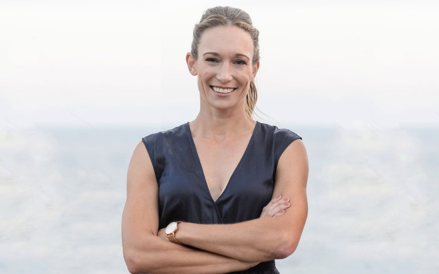 Dr. Christine Theiss lacht mit gekreuzten Armen am Meer