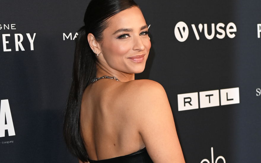 Amira Pocher schaut auf der Berlinale über ihre Schulter und lächelt