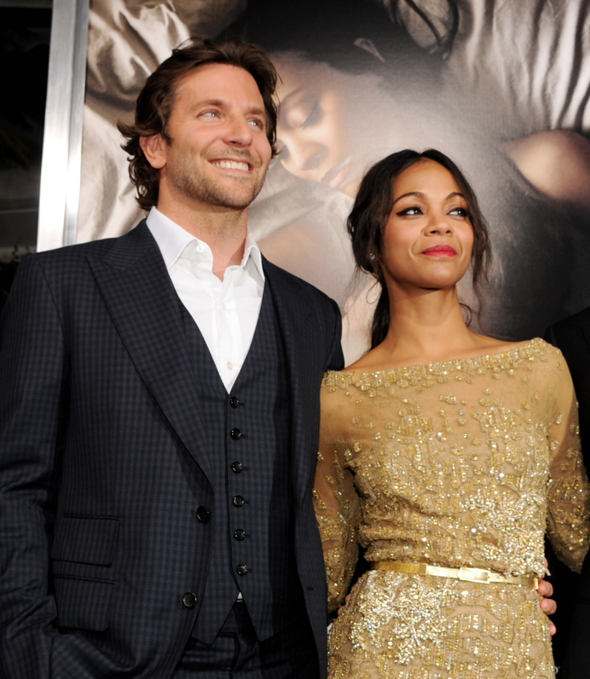 Bradley Cooper im Anzug und Zoe Saldaña im goldenen Kleid stehen nebeneinander