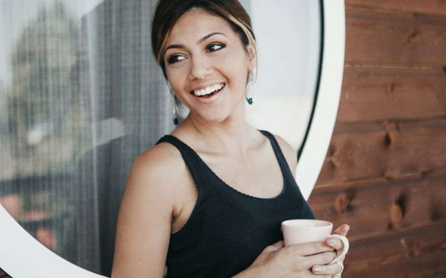 frau hält becher mit kaffee-alternative in der hand und lacht