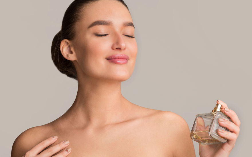 frau sprüht sich mit parfum ein und genießt den Duft