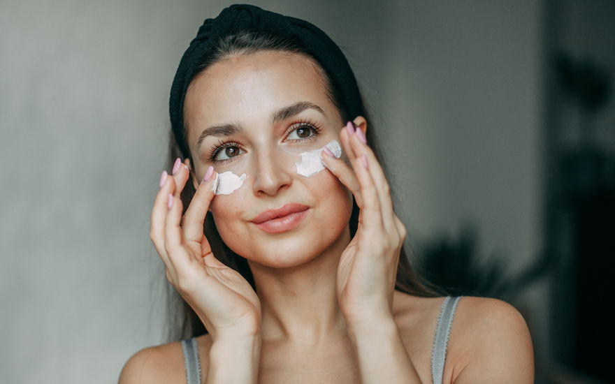 Frau mit Anti-Aging-Creme auf Wange