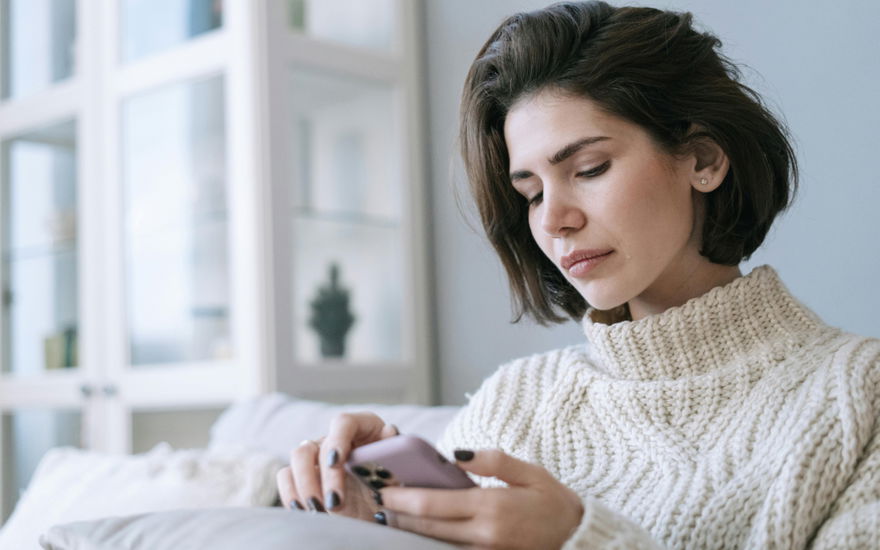 Frau schaut traurig auf ihr Smartphone
