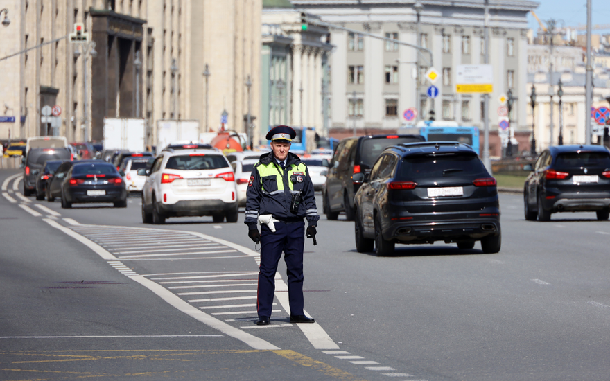 Polizist steht auf der Straße hinter fahrenden Autos
