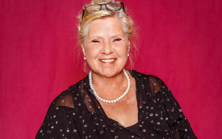 Silvia Wollny lächelt mit Brille auf dem Kopf und Perlenhalskette