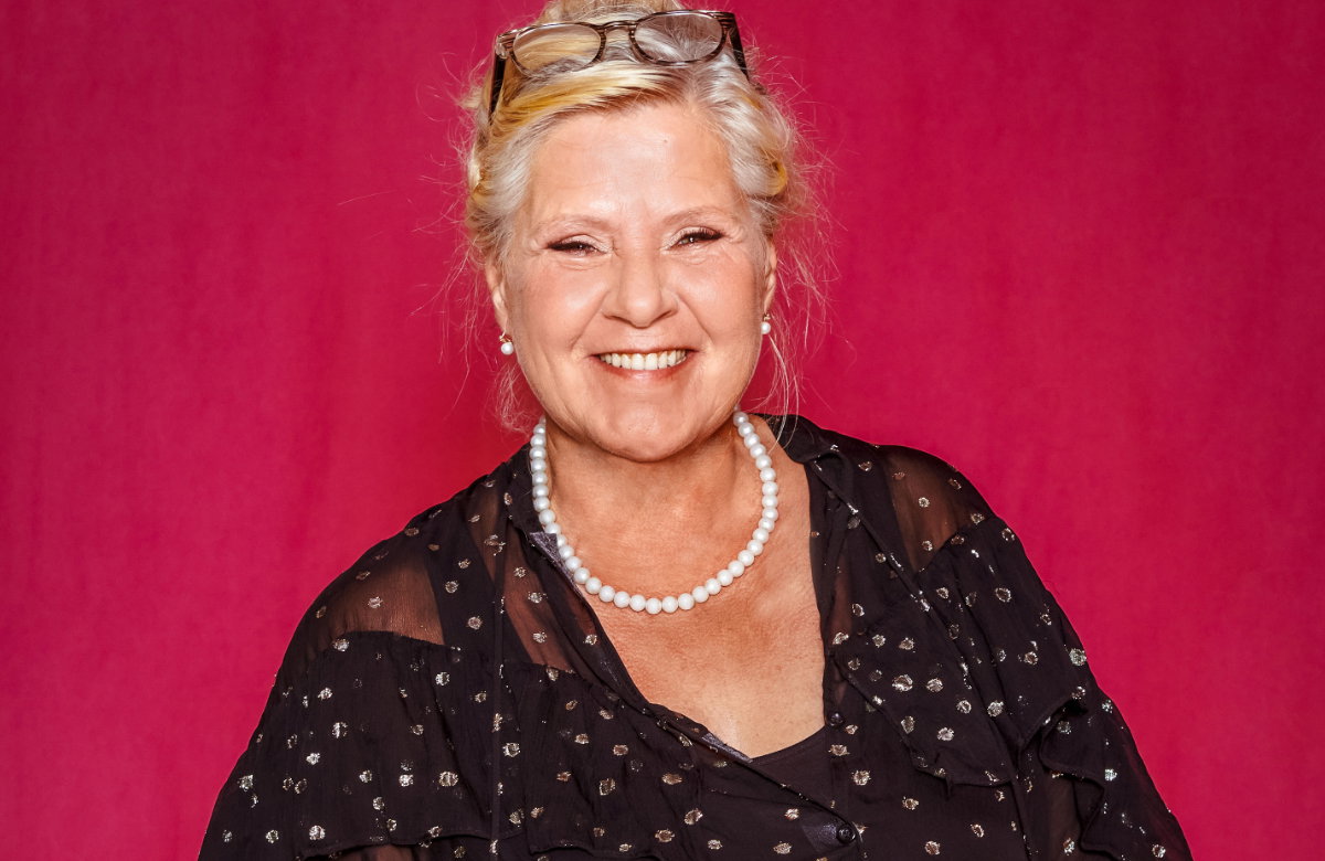 Silvia Wollny lächelt mit Brille auf dem Kopf und Perlenhalskette