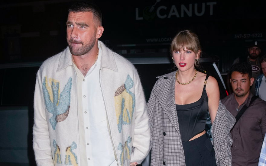 Travis Kelce und Taylor Swift halten sich an der Hand mit angespannten Gesichtsausdrücken