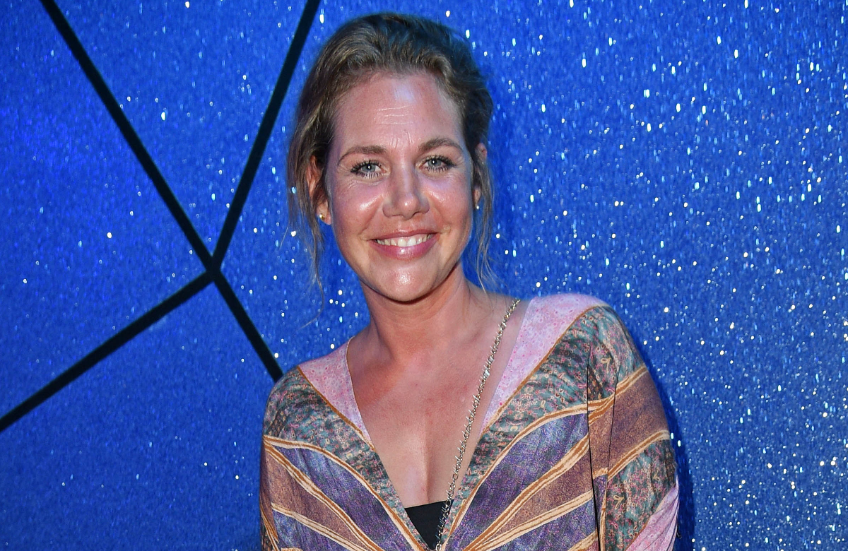 Felicitas Woll lächelt vor einem blauen Hintergrund