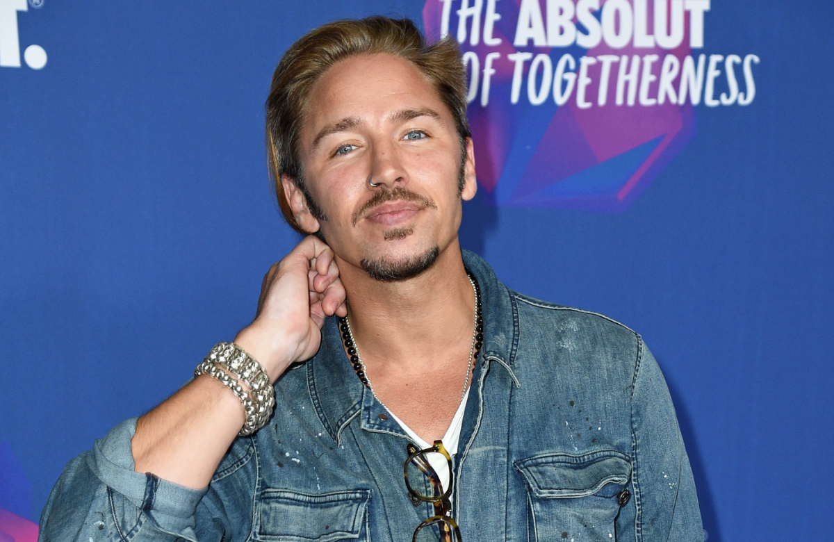 Gil Ofarim posiert vor einer blauen Wand