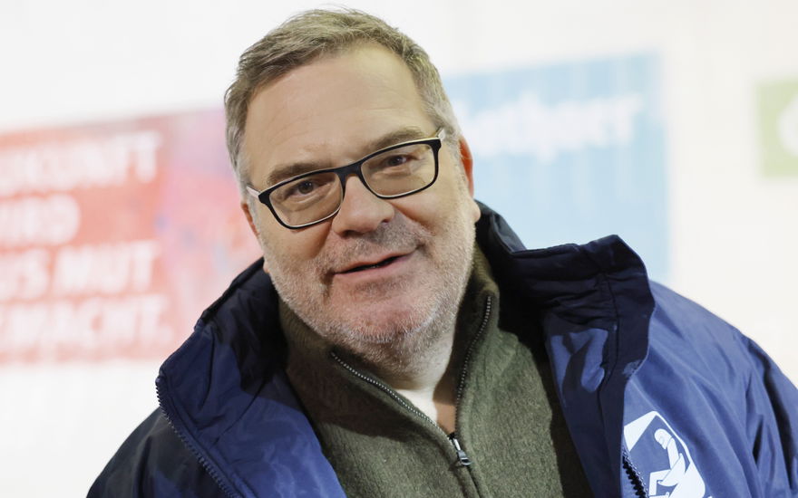 Moderator Elton lächelt leicht