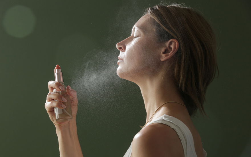 Frau fixiert Make-up mit Fixing Spray