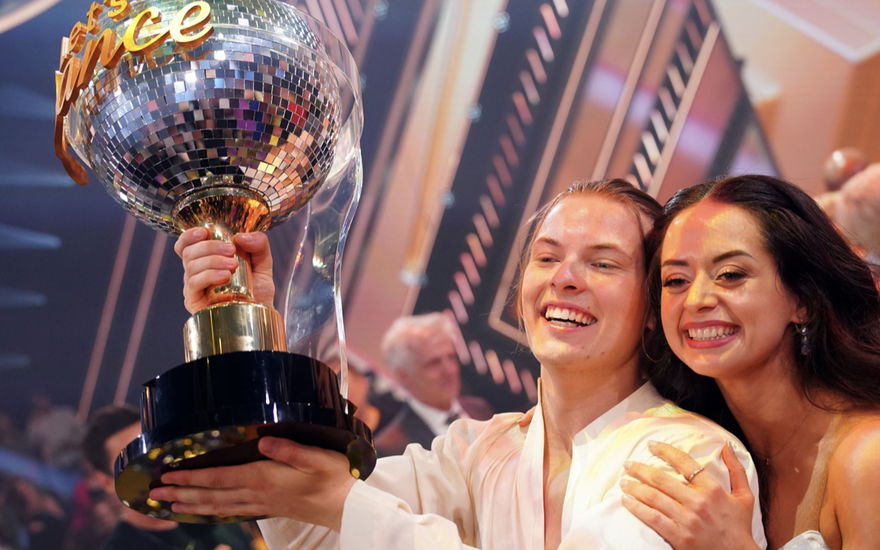 Gabriel Kelly hält den "Let's Dance"-Siegerpokal hoch und Malika Dzumaev umarmt ihn