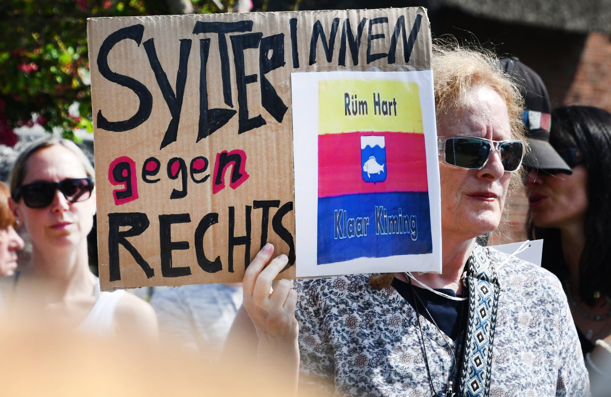 Frau demonstriert nach Rassismus-Skandal auf Sylt mit Plakat