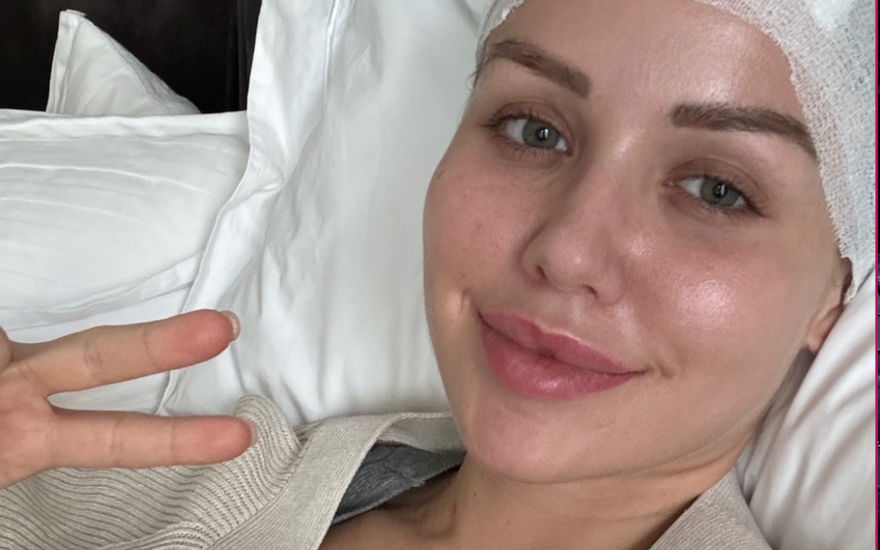 Kim Gloss mit Verband um den Kopf im Krankenhausbett