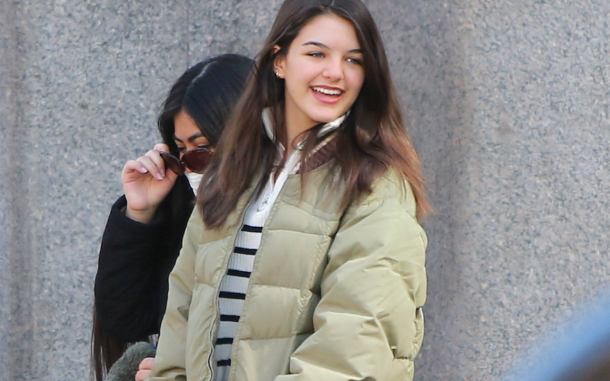 Suri Cruise schaut zur Seite und lacht, hält eine pinke Hundeleine in der Hand