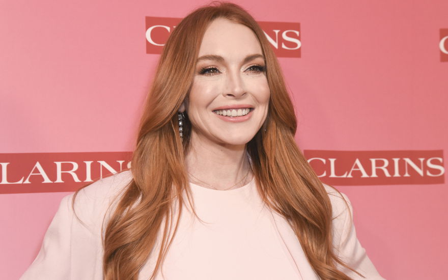 Lindsay Lohan strahlt vor pinkem Hintergrund