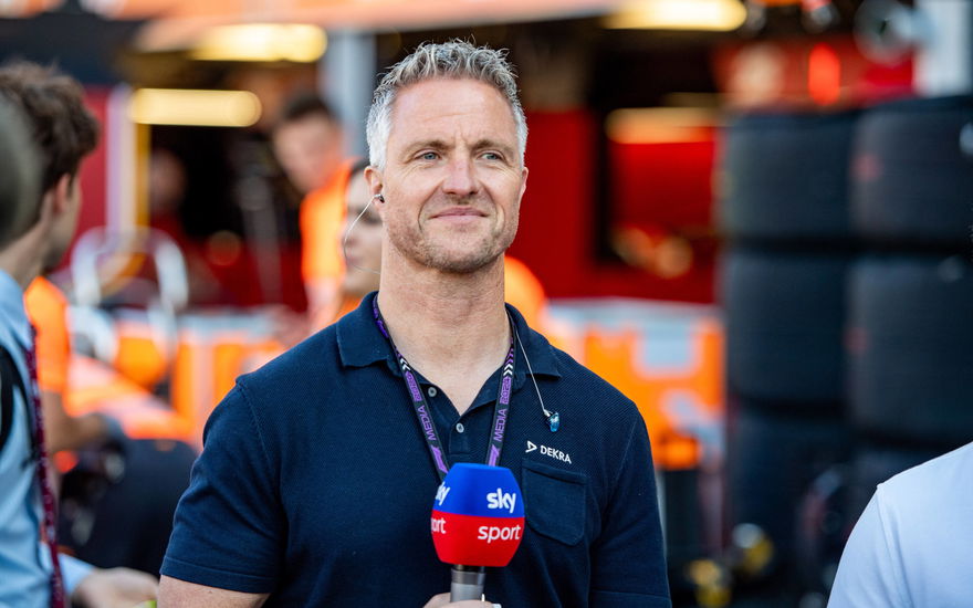 Ralf Schumacher lächelt mit Mikrofon von der Hand