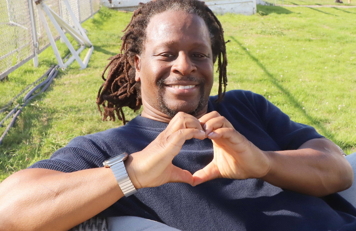 Mola Adebisi formt mit seinen Händen ein Herz