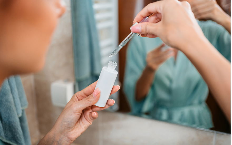 Frau mit Pipette vor Spiegel