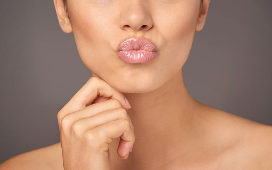 Frau formt Kussmund mit Lipgloss