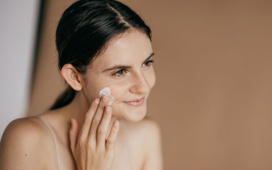 Frau trägt Anti-Aging-Creme auf Wangen auf