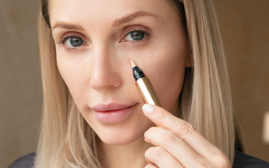 Frau trägt Concealer unter Augen auf