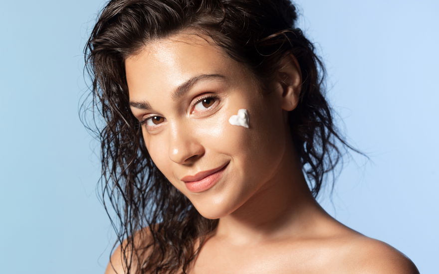 Frau mit Anti-Aging-Creme in Herzform