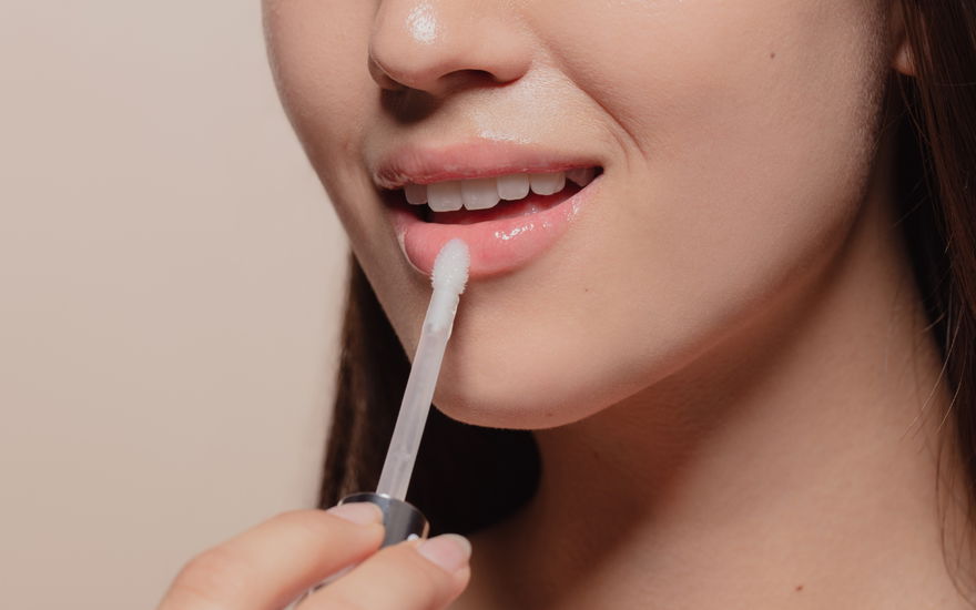 Frau trägt Lippenöl auf