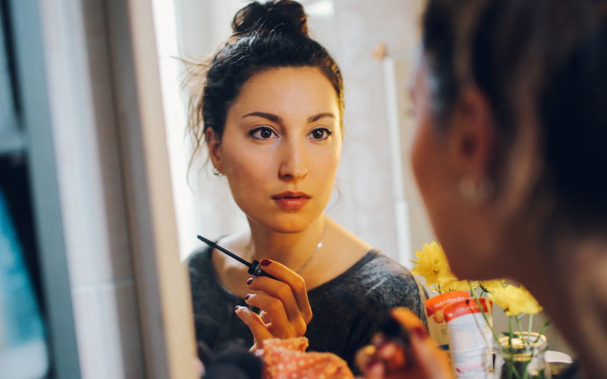 Frau mit Mascara vor Spiegel