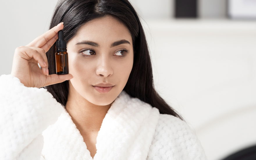 Frau mit Anti-Aging-Flasche vor Gesicht