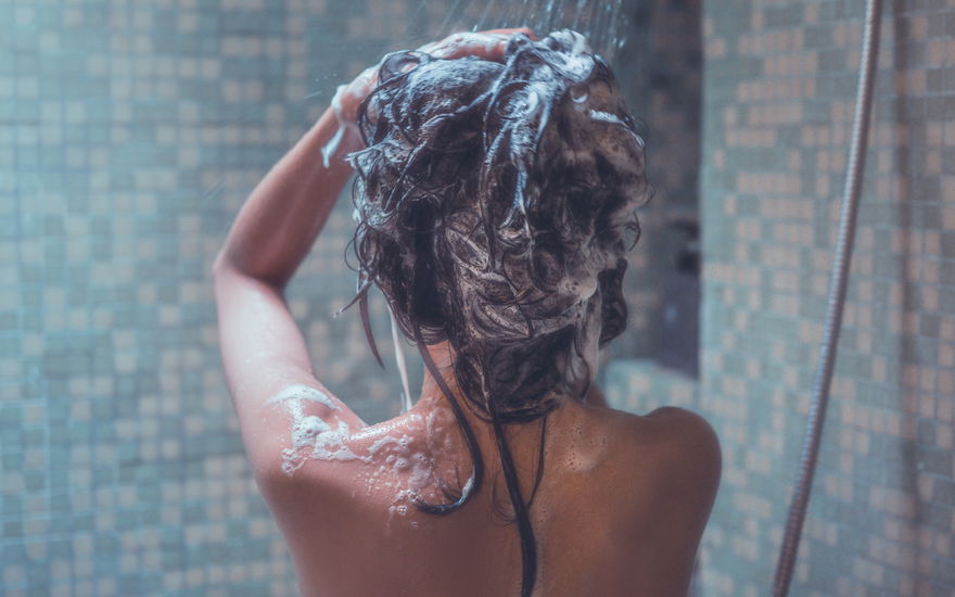 Frau wäscht Haare unter der Dusche
