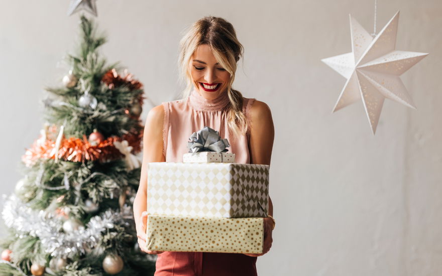 Frau vor Tannenbaum mit Geschenken