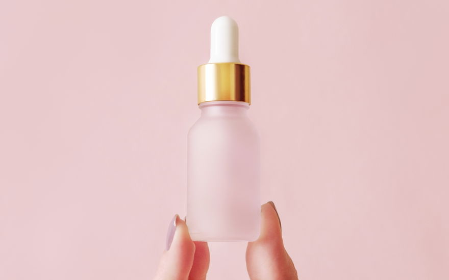 Frau mit Serum-Flasche zwischen Finge