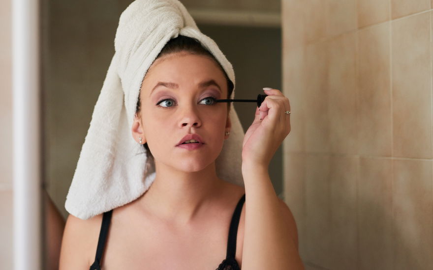 Frau vor Spiegel tuscht Wimpern