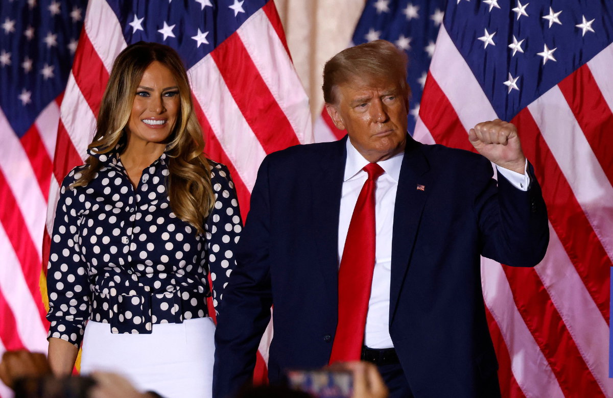 Melania & Donald Trump mit USA-Flaggen im Hintergrund