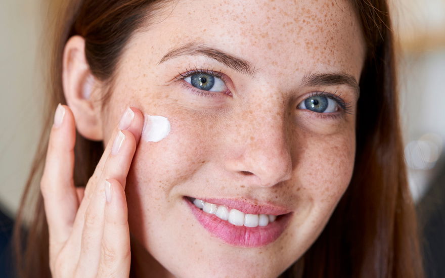 Frau mit Sommersprossen Creme unter Augen